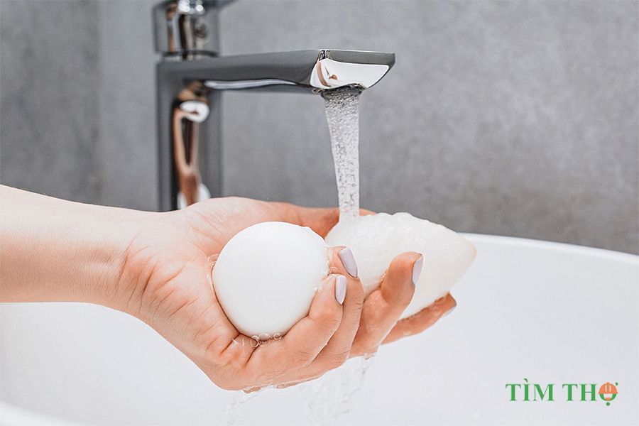 Giữ miếng mút trang điểm dưới vòi nước ấm đang chảy